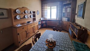 A dining area with a table set for two, surrounded by wooden cabinets and a bookshelf filled with books.