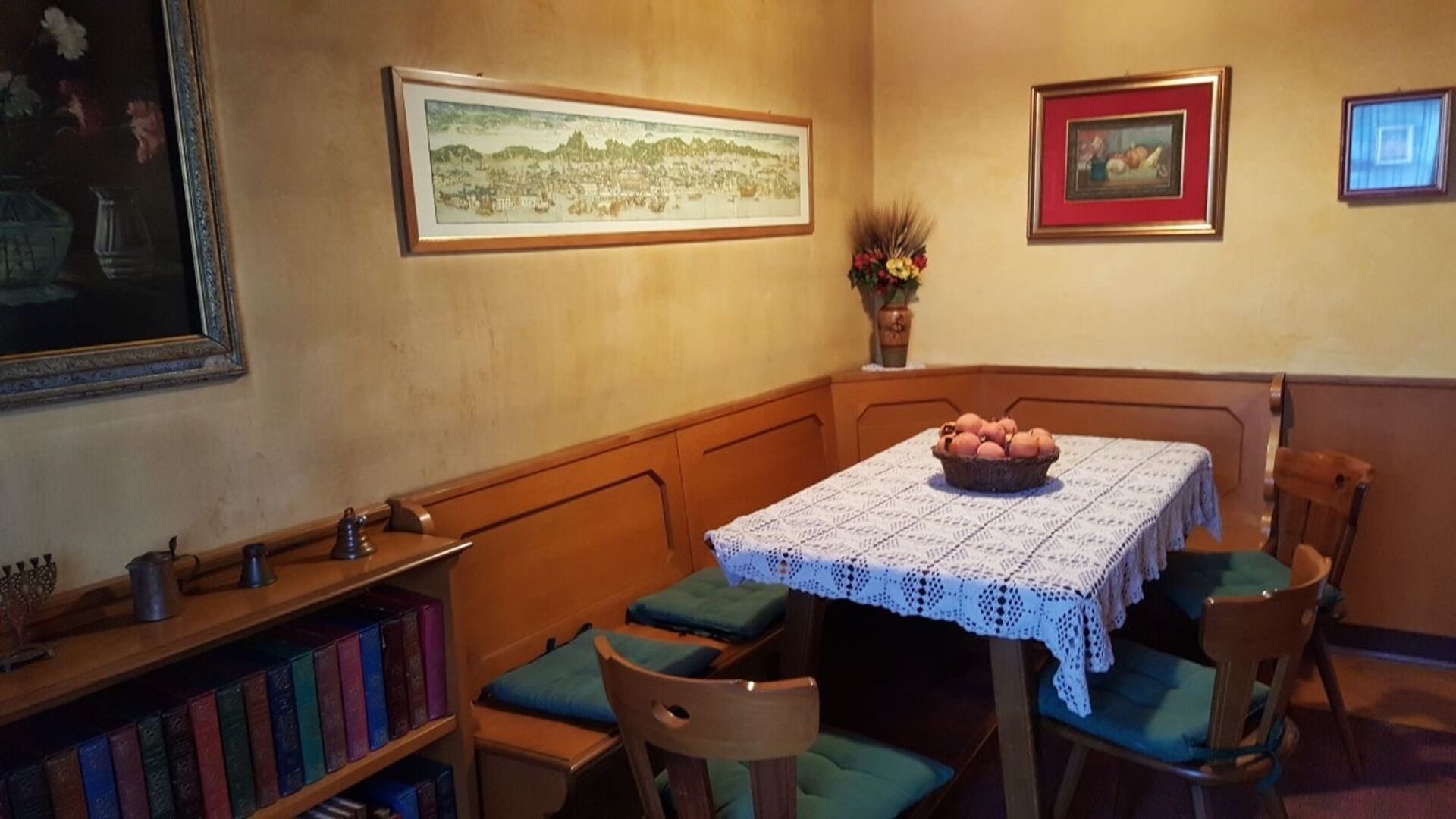 Un rincón comedor acogedor con una mesa de madera, sillas verdes con cojines y una cesta de pan sobre la mesa.