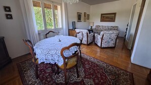 A dining area with a round table, chairs, a chandelier, and a patterned rug.