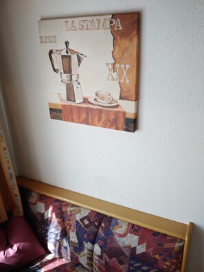 A wall with a vintage coffee advertisement and a colorful abstract painting below it. - Pension Weirather (Imst)