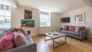 A modern living room with two grey sofas, a wooden coffee table, and artwork on the walls. - Dawson Place (London)