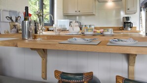 Une cuisine dotée de plans de travail en bois, d’une machine à café, d’un four à micro-ondes et d’une fenêtre donnant sur un paysage verdoyant.