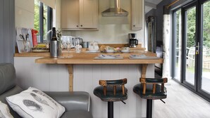 Une cuisine moderne avec des plans de travail en bois, un îlot central, des tabourets de bar et de grandes fenêtres.