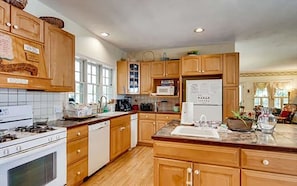 A kitchen with wooden cabinets, a stove, a microwave, and a refrigerator. - West Tisbury Inn (Vineyard Haven)