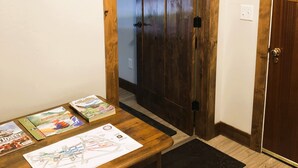 A wooden door with a black doorknob, a wooden bench with magazines, and a black doormat. - Cozy spacious king bed suite, In the heart of Historic Helena, Montana! (Helena)