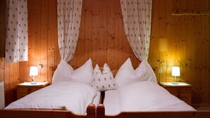 A wooden-paneled room with a bed, two bedside tables, and a nightstand. - Sportappart Schatz (Imst)