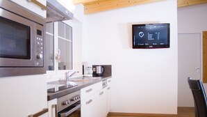 A modern kitchen with a built-in microwave, coffee maker, and a digital clock on the wall. - Sportappart Schatz (Imst)