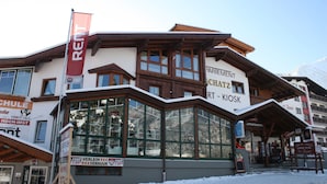 A building with a ski resort sign, large windows, and a wooden facade. - Sportappart Schatz (Imst)