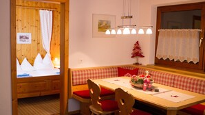 A cozy dining area with a wooden table, red cushioned benches, and a small Christmas tree. - Sportappart Schatz (Imst)