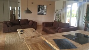 Una sala moderna con dos sofás marrones, una mesa de centro de madera y una zona de cocina con estufa.