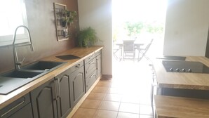 Una cocina con pileta, mesada, alacenas y un comedor con sillas.