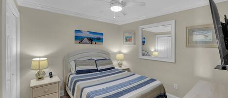 A bedroom with a bed, nightstands, a ceiling fan, and wall art.