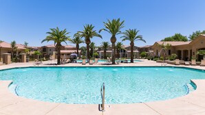 A swimming pool with palm trees and lounge chairs, surrounded by buildings with a Mediterranean architectural style. - Luxury Heated Pool, Spa & Gym- 4BR Mesa Townhome (Mesa)