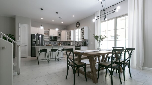 A modern kitchen with white cabinets, a wooden dining table, and bar stools. - Luxury Heated Pool, Spa & Gym- 4BR Mesa Townhome (Mesa)