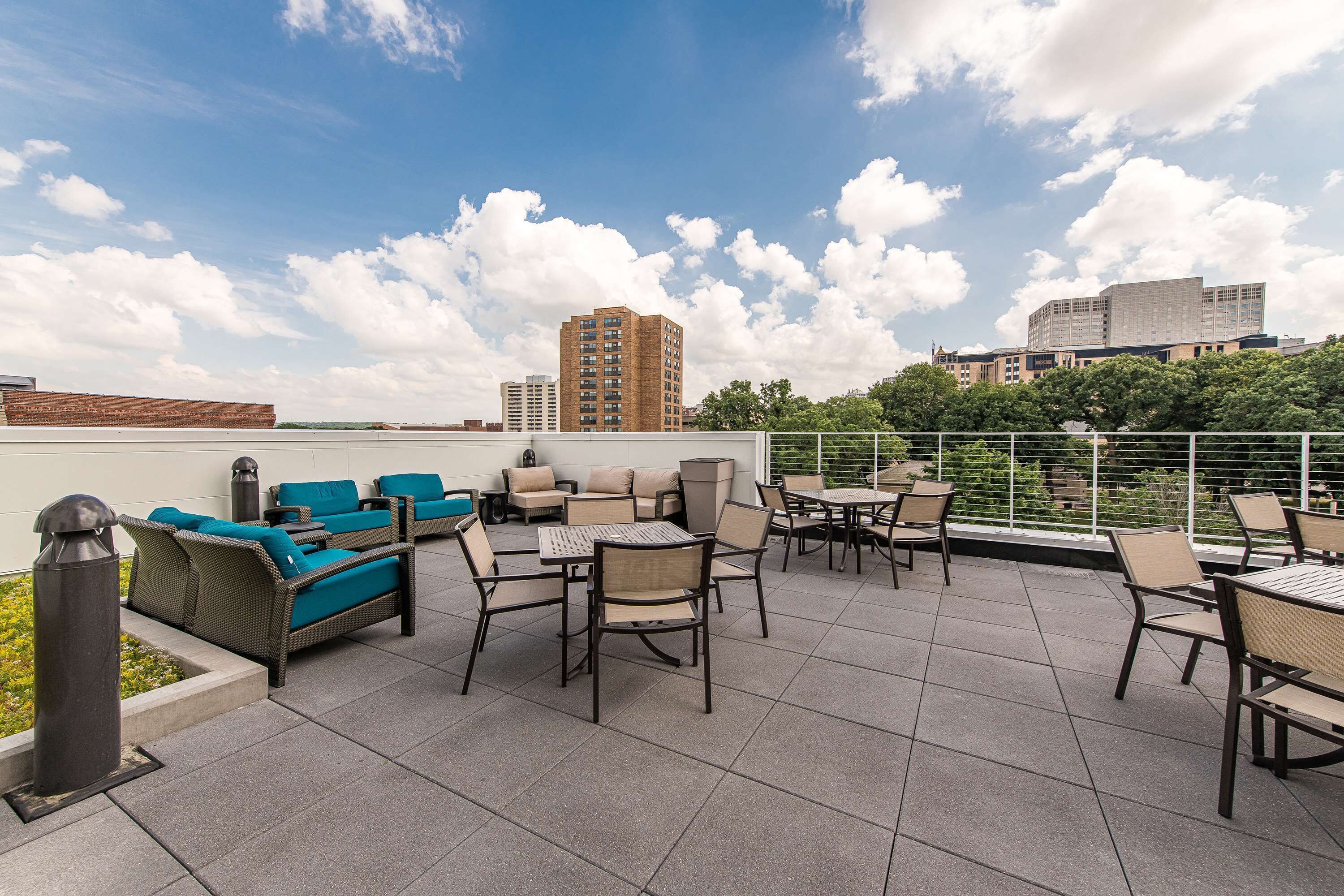 Une terrasse sur le toit, aménagée avec du mobilier d’extérieur, offrant une vue sur le paysage urbain et un ciel dégagé.
