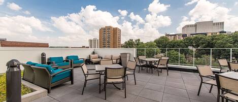 Une terrasse sur le toit, aménagée avec du mobilier d’extérieur, offrant une vue sur le paysage urbain et un ciel dégagé.