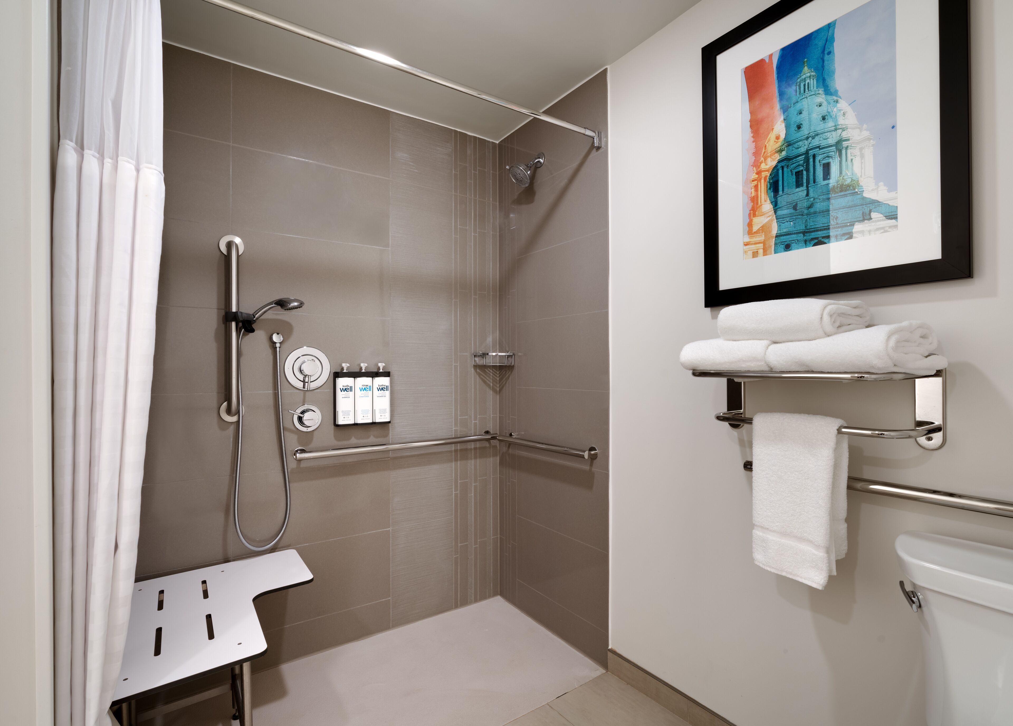 A modern bathroom with a shower, toilet, and a framed picture on the wall.