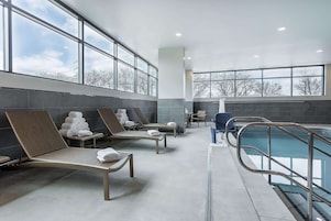 Un área de piscina interior moderna con sillones de descanso y una piscina.