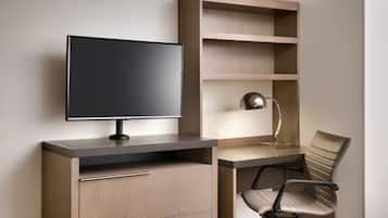 A modern office desk with a flat-screen monitor, a lamp, and a chair.