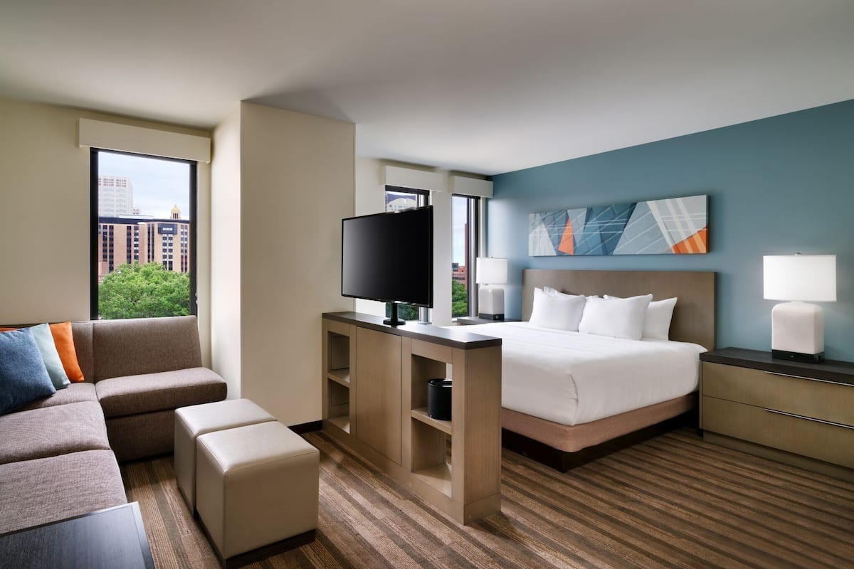 A hotel room with a bed, a TV, a sofa, and a desk.