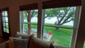 Una habitación acogedora con ventanas amplias, una zona de comedor y vistas a un área verde con árboles.
