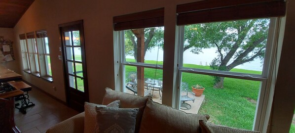 A cozy room with large windows, a dining area, and a view of a grassy area and tree.