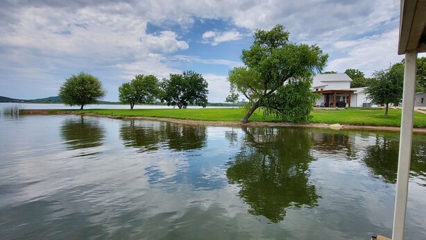 Vista de un lago con una casa y árboles.