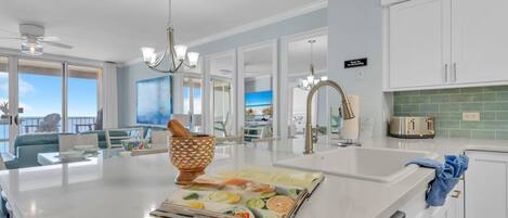Una cocina moderna con una isla grande, muebles blancos y vistas al exterior.