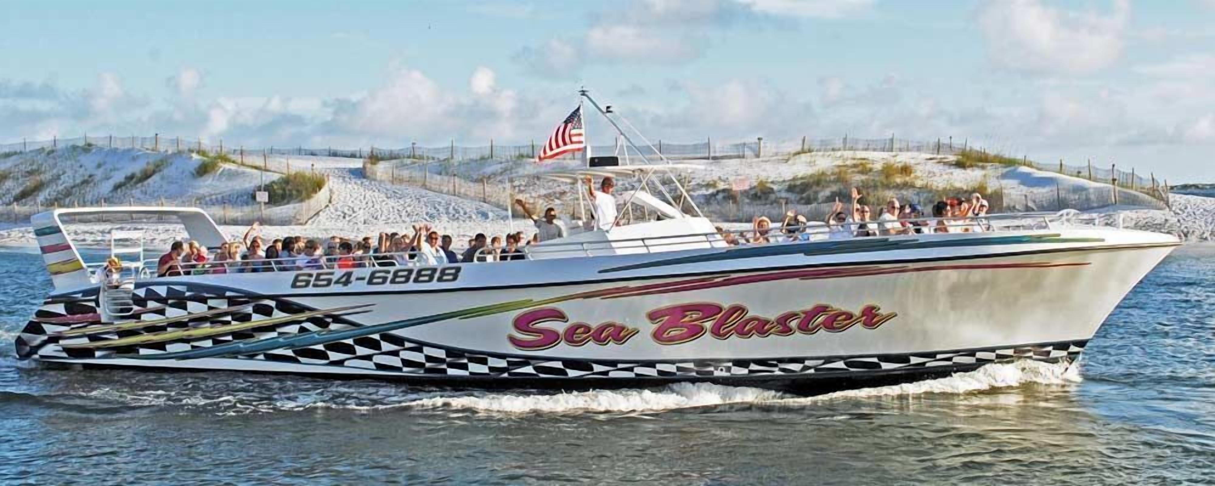 Un velocitaris anomenat 'Sea Blaster' amb el número 654-6888, navegant sobre l'aigua davant d'una platja sorrenca i dunes.