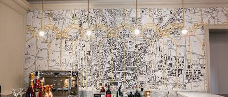 Zona de bar con un mural de mapa, barra y varias botellas de alcohol.