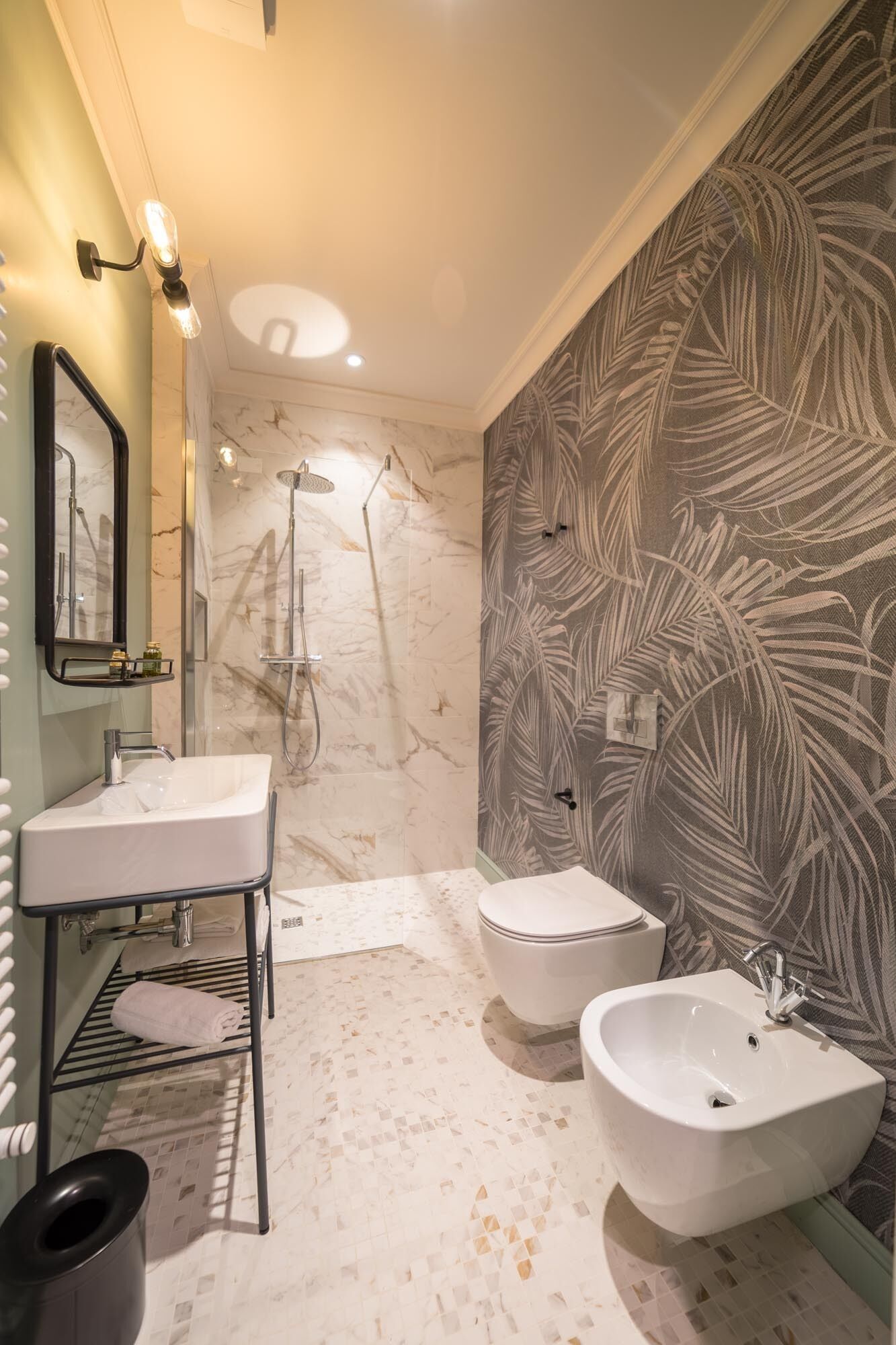 A modern bathroom with a marble shower, two sinks, a toilet, and a large mirror.