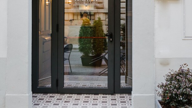 Entrada de hotel con puerta negra, un letrero que dice "Palazzo 42" y piso de baldosas.
