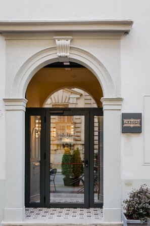 A hotel entrance with a black door, a sign reading "Palazzo 42", and a tiled floor.