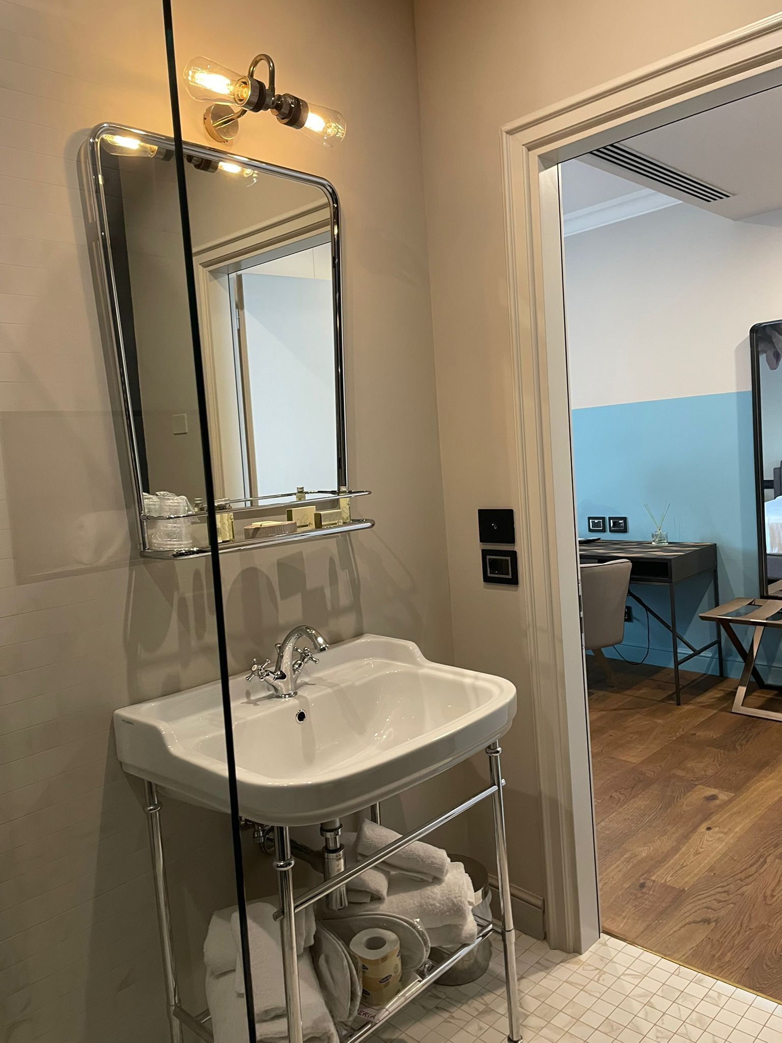 A bathroom with a white sink, a mirror, and a towel rack.