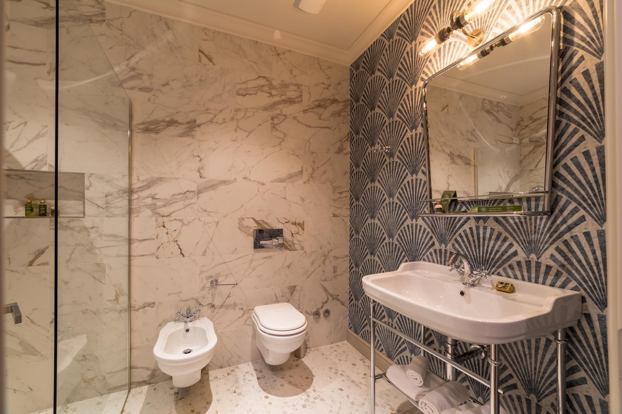 A bathroom with a bidet, toilet, and a sink with a mirror.
