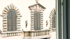 Fachada de edificio con ventanas arqueadas, un frontón central y elaborados detalles de piedra.