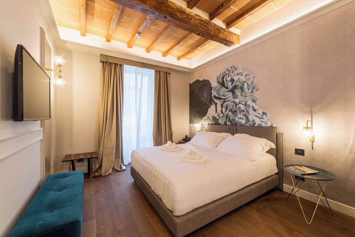 Una habitación de hotel con una cama grande, un televisor de pantalla plana, un escritorio y un cuadro en la pared.