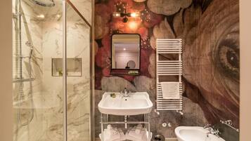 A bathroom with a marble shower, two sinks, a mirror, and a towel rack.