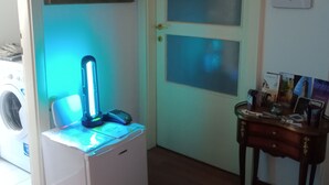 A room with a washing machine, a desk with a lamp, a door with frosted glass panels, and a wall with a framed picture and some papers. - B&B Maddalena di San Zeno (Verona)