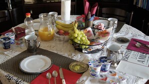 A breakfast table set with plates, cutlery, a fruit bowl, and various breakfast items. - B&B Maddalena di San Zeno (Verona)