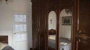 A bedroom with a large wooden wardrobe, a bed with a white pillow, and a cross on the wall. - B&B Maddalena di San Zeno (Verona)