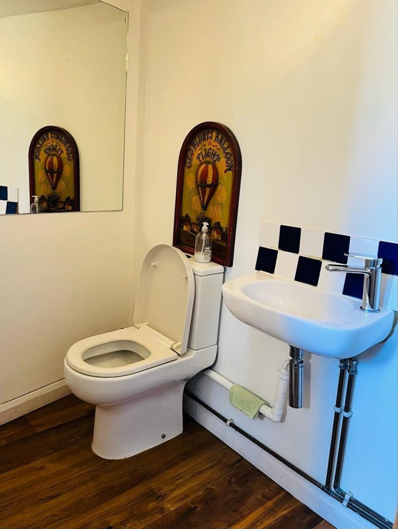 A bathroom with a white toilet, a sink with a chrome faucet, and a mirror.