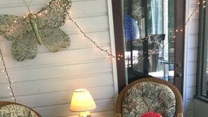 A cozy seating area with wicker chairs, a small orange ottoman, and a hexagonal patterned rug.