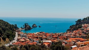 A coastal town with red-roofed buildings, a clear blue sea, and rocky outcrops. - Penthouse sea view suite (Parga)