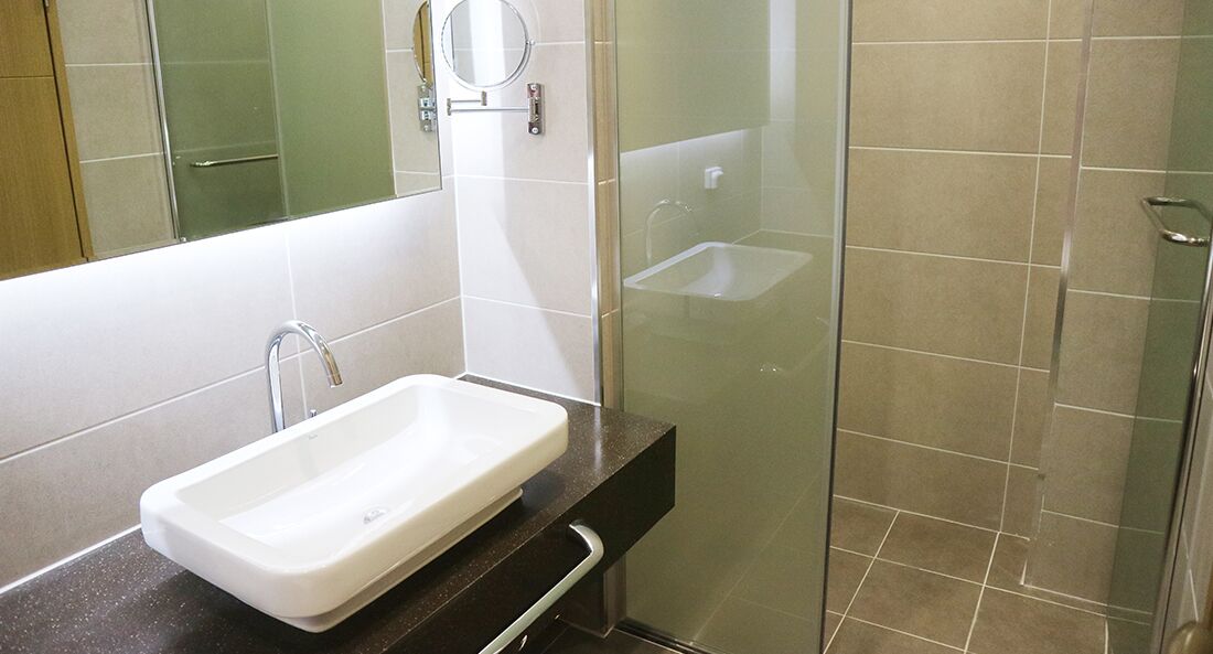 A bathroom with a white sink, a mirror, and a glass shower enclosure.