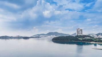 A coastal cityscape with a calm sea, a prominent building, and distant mountains.