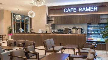 A cafe with a modern interior, featuring a counter with a coffee machine and a refrigerated display case.