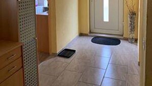 Un pasillo con un armario de madera, una puerta y piso de baldosas.
