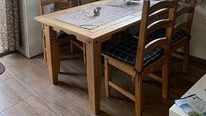 Un comedor con una mesa y sillas de madera, un televisor y un ventanal con cortinas.