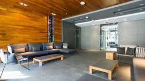 En moderne lobby med træloft, grå sofaer og et sofabord.